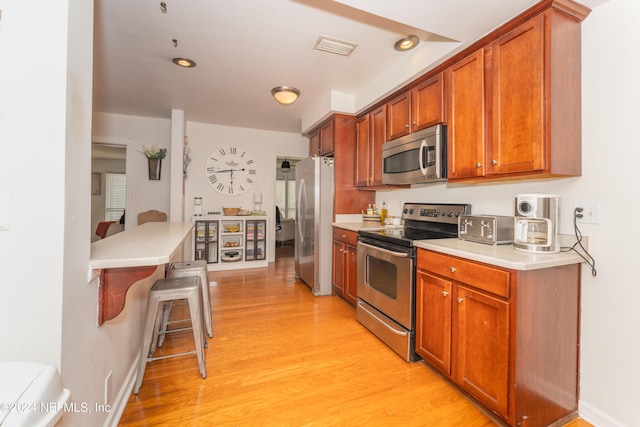 kitchen with stainless steel appliances, a breakfast bar area, and light wood-type flooring