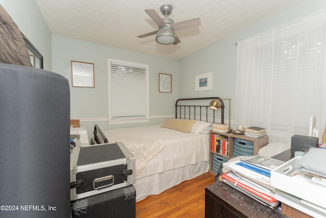 bedroom featuring a textured ceiling, ceiling fan, and wood-type flooring