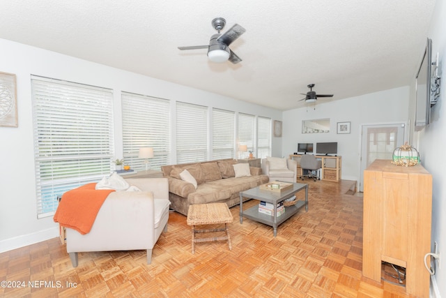 living room with a textured ceiling, ceiling fan, and light parquet floors