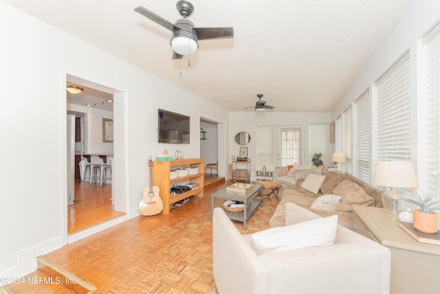 living room with a textured ceiling, ceiling fan, and light parquet floors