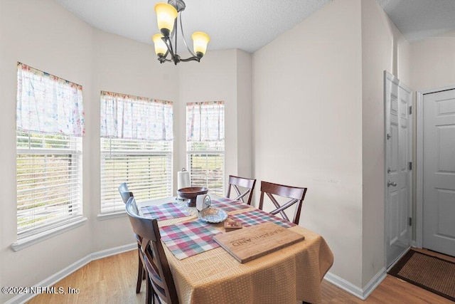 dining room featuring a chandelier, a textured ceiling, and light wood-type flooring