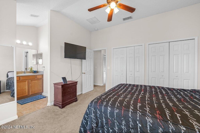 bedroom with light carpet, ensuite bathroom, two closets, ceiling fan, and sink