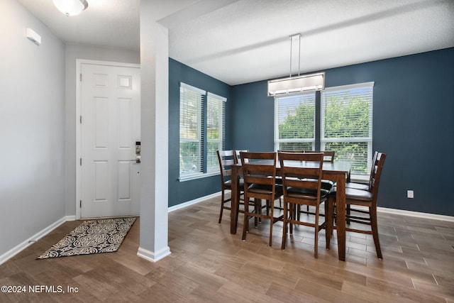 dining space featuring a textured ceiling, hardwood / wood-style flooring, and a wall mounted AC