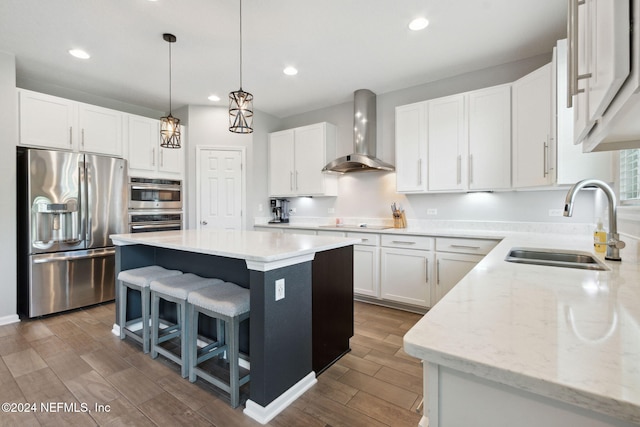 kitchen featuring white cabinets, wood-type flooring, stainless steel appliances, and wall chimney exhaust hood