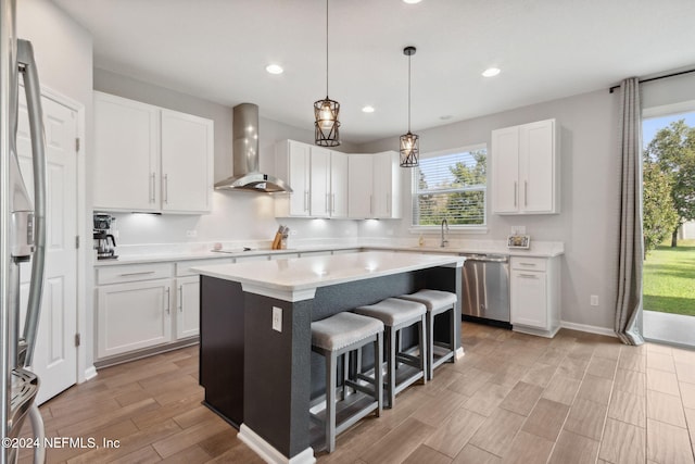 kitchen featuring white cabinets, appliances with stainless steel finishes, a wealth of natural light, and wall chimney range hood