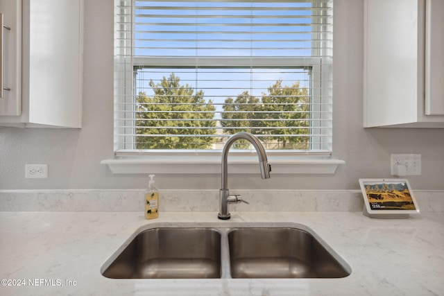 details featuring light stone counters, sink, and white cabinets