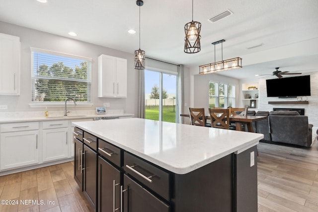 kitchen with white cabinets, plenty of natural light, light wood-type flooring, and decorative light fixtures