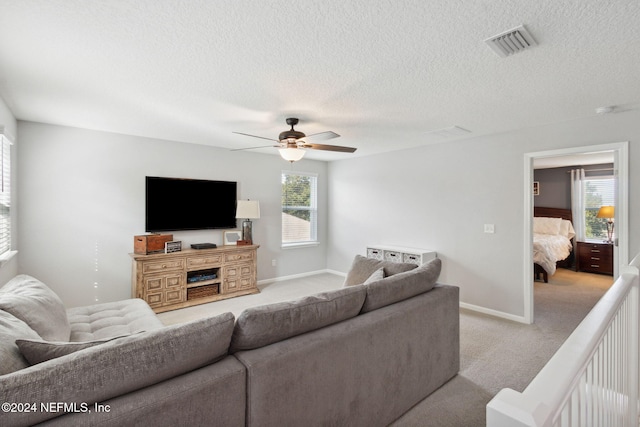 living room featuring a textured ceiling, ceiling fan, and light carpet