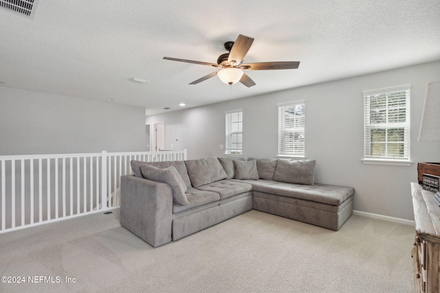 living room featuring light carpet, ceiling fan, and a textured ceiling