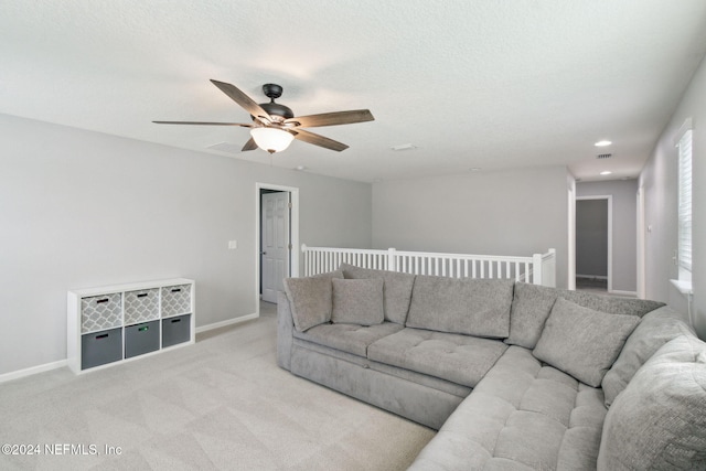 carpeted living room featuring ceiling fan and a textured ceiling