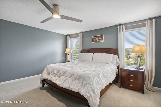 carpeted bedroom featuring ceiling fan and a textured ceiling