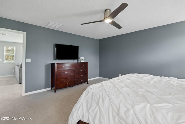 carpeted bedroom featuring ceiling fan and a textured ceiling