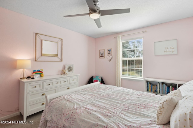 carpeted bedroom with ceiling fan and a textured ceiling