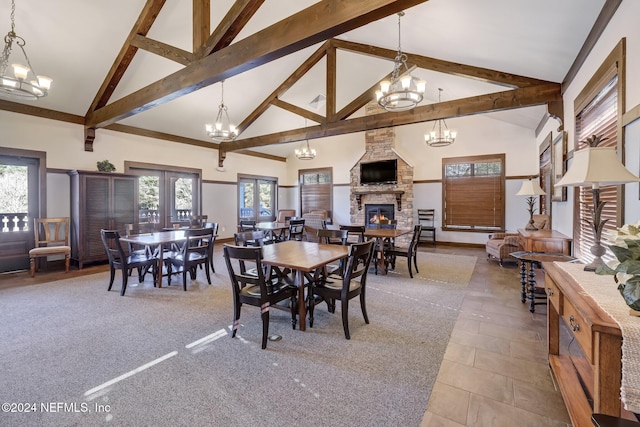 carpeted dining area featuring a healthy amount of sunlight, a stone fireplace, beam ceiling, and high vaulted ceiling