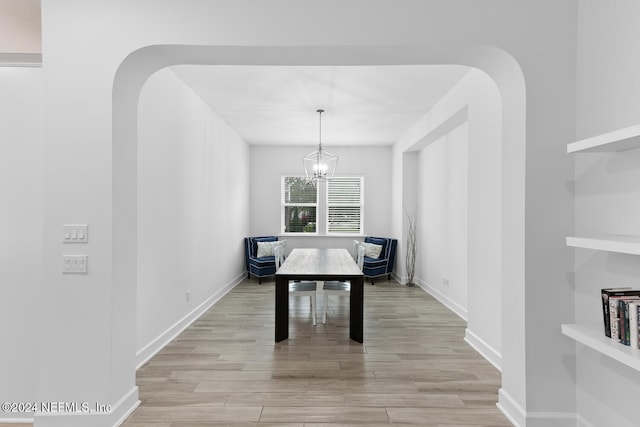 dining area with light hardwood / wood-style floors and an inviting chandelier