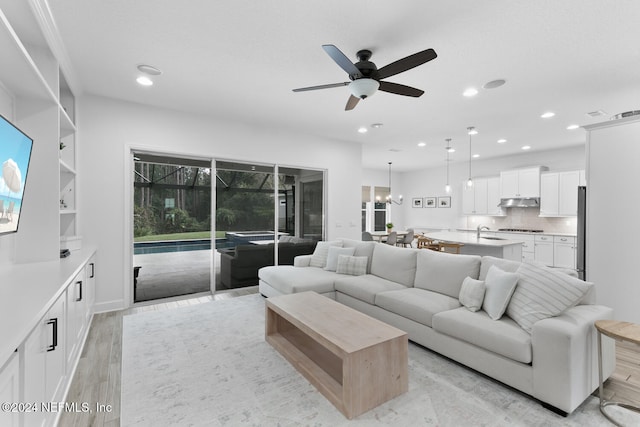 living room with light hardwood / wood-style flooring, ceiling fan, and sink