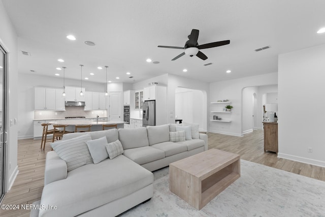 living room with ceiling fan, sink, and light hardwood / wood-style flooring