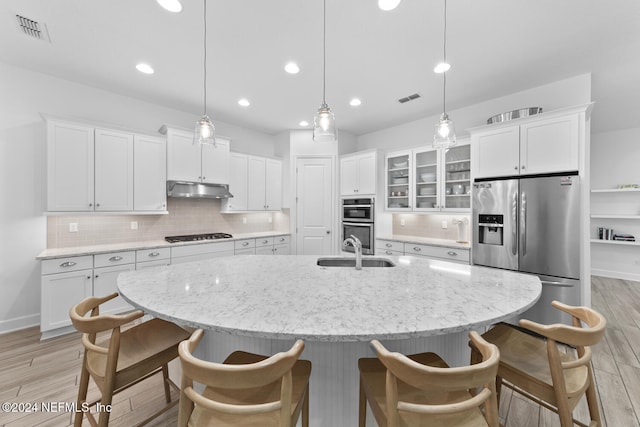 kitchen with decorative backsplash, white cabinets, light hardwood / wood-style floors, and decorative light fixtures