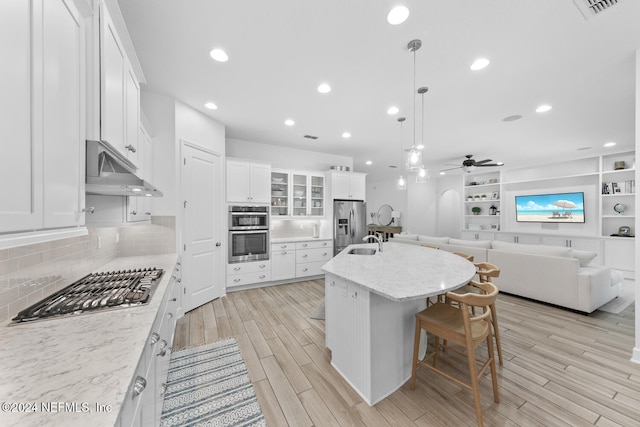 kitchen featuring pendant lighting, a center island, stainless steel appliances, and white cabinetry