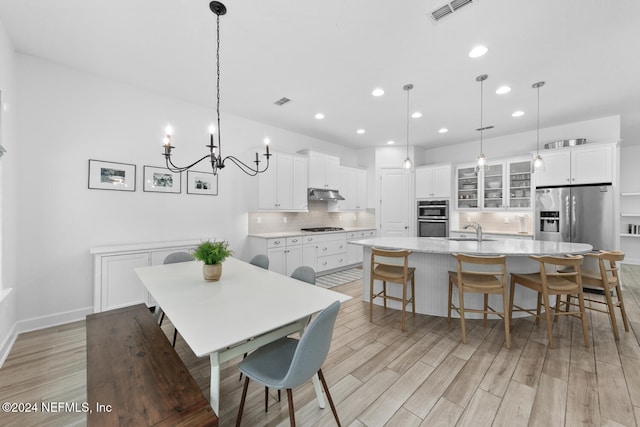 dining space with an inviting chandelier, light hardwood / wood-style flooring, and sink