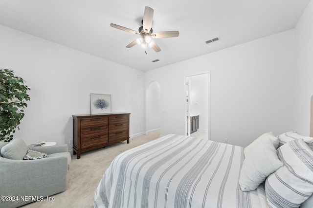 bedroom with ceiling fan, light carpet, and ensuite bath