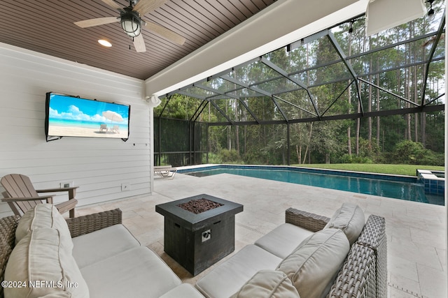 view of pool with a patio area, an outdoor living space with a fire pit, and a lanai