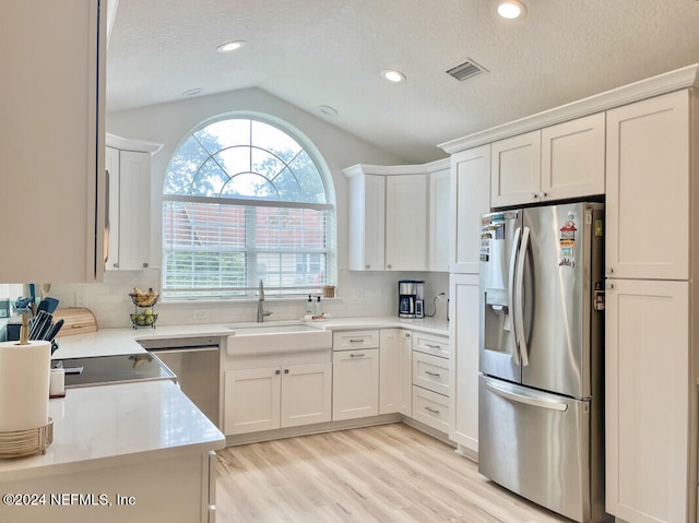 kitchen featuring white cabinets, sink, lofted ceiling, and stainless steel appliances