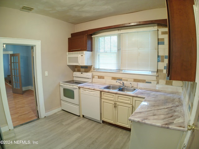 kitchen with light stone countertops, sink, light hardwood / wood-style floors, and white appliances