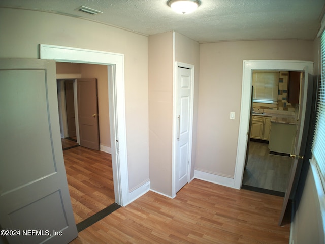 corridor featuring a textured ceiling and light wood-type flooring