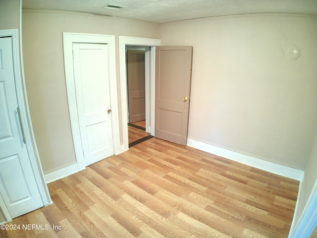 unfurnished bedroom with light wood-type flooring and a textured ceiling