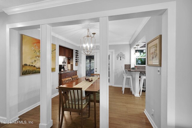 dining area featuring hardwood / wood-style flooring, ornamental molding, and a chandelier