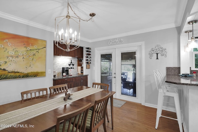 dining room featuring crown molding, french doors, an inviting chandelier, and hardwood / wood-style flooring