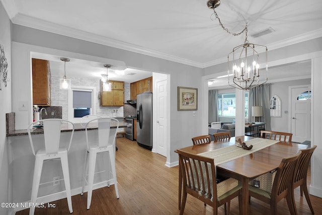 dining space featuring light hardwood / wood-style floors, ornamental molding, and a notable chandelier