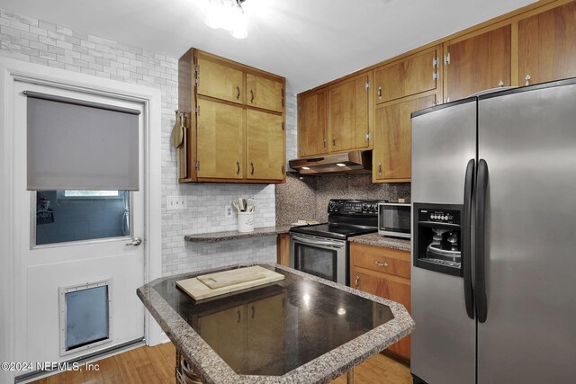 kitchen featuring decorative backsplash, appliances with stainless steel finishes, and light hardwood / wood-style flooring