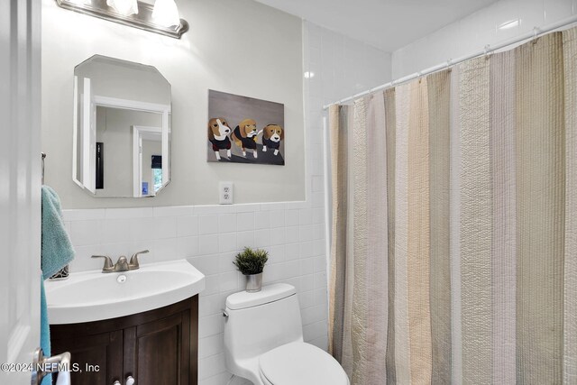 bathroom with a shower with curtain, vanity, tile walls, and toilet