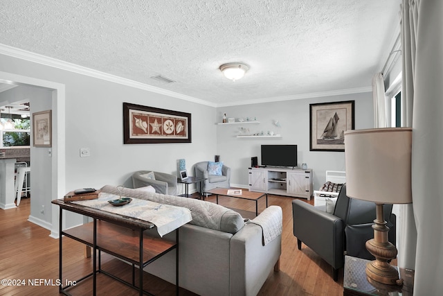 living room featuring a textured ceiling, wood-type flooring, and ornamental molding