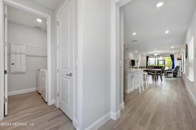 hall featuring washer and dryer, electric panel, and light hardwood / wood-style floors