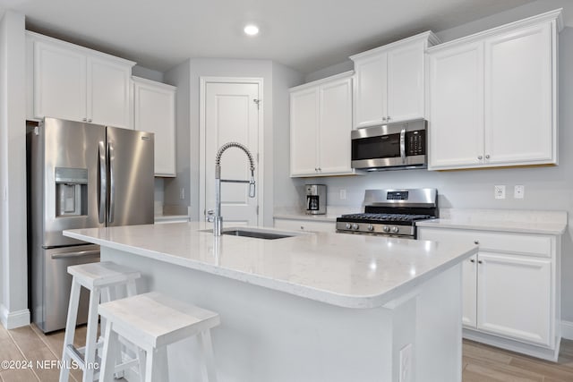 kitchen featuring an island with sink, stainless steel appliances, light hardwood / wood-style flooring, and sink