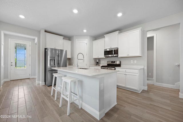 kitchen with sink, stainless steel appliances, light hardwood / wood-style flooring, a center island with sink, and white cabinets