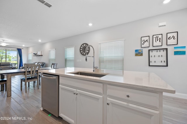 kitchen with light stone counters, light hardwood / wood-style floors, white cabinetry, and sink