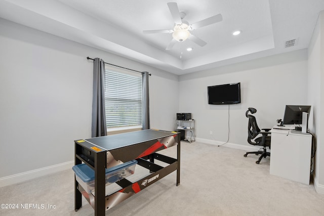 carpeted office featuring a tray ceiling and ceiling fan