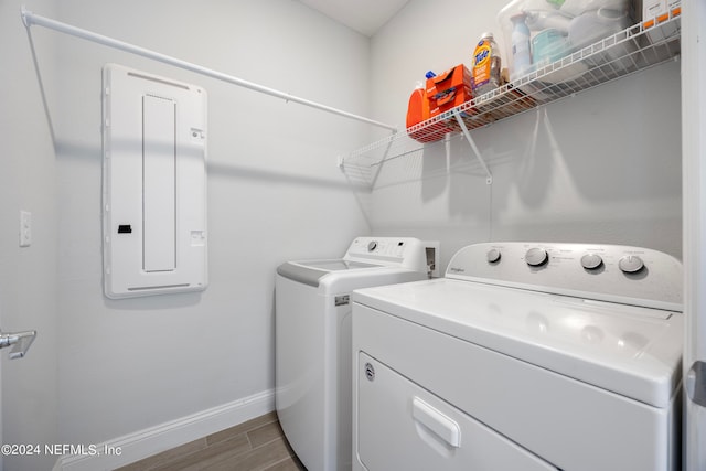 washroom featuring hardwood / wood-style floors, washing machine and dryer, and electric panel