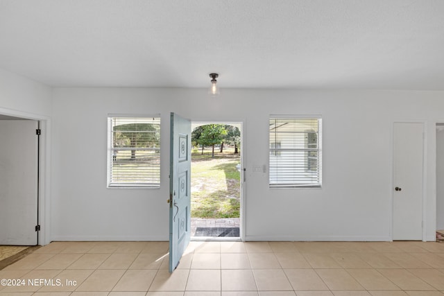 foyer with light tile patterned floors and a textured ceiling