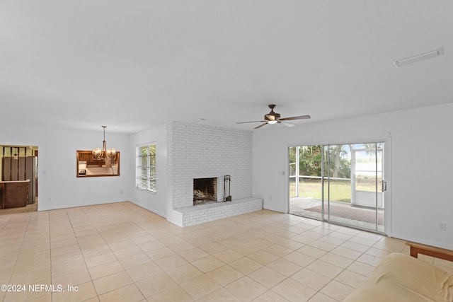 unfurnished living room with ceiling fan with notable chandelier, light tile patterned flooring, and a fireplace