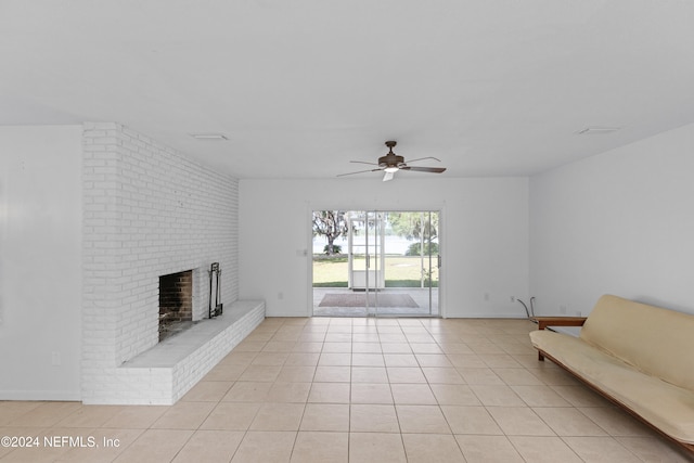 unfurnished living room with a brick fireplace, ceiling fan, and light tile patterned flooring