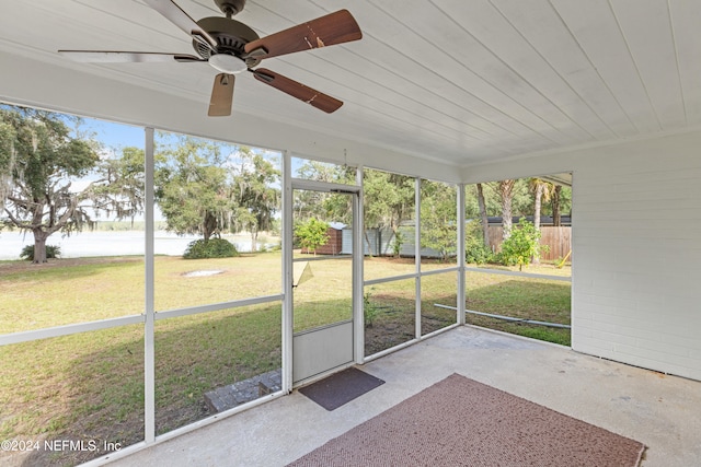 unfurnished sunroom featuring ceiling fan, wood ceiling, and a wealth of natural light