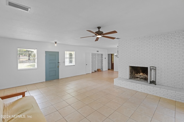 unfurnished living room featuring ceiling fan, a fireplace, light tile patterned floors, and brick wall