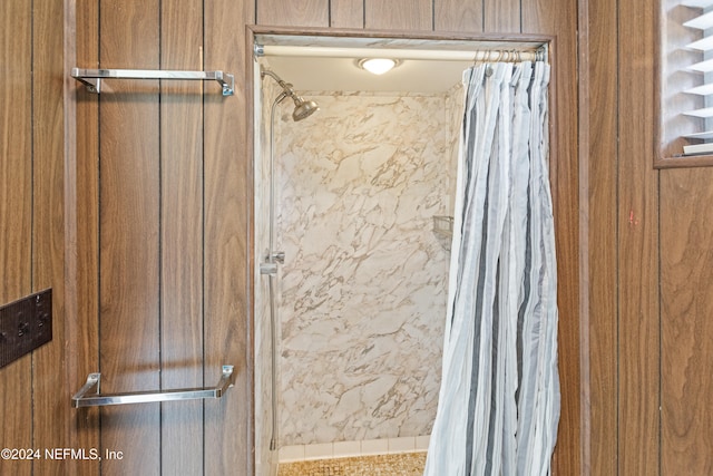 bathroom with curtained shower and wood walls