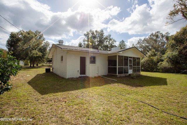 rear view of house featuring a sunroom and a yard