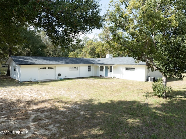 rear view of house featuring central air condition unit and a lawn